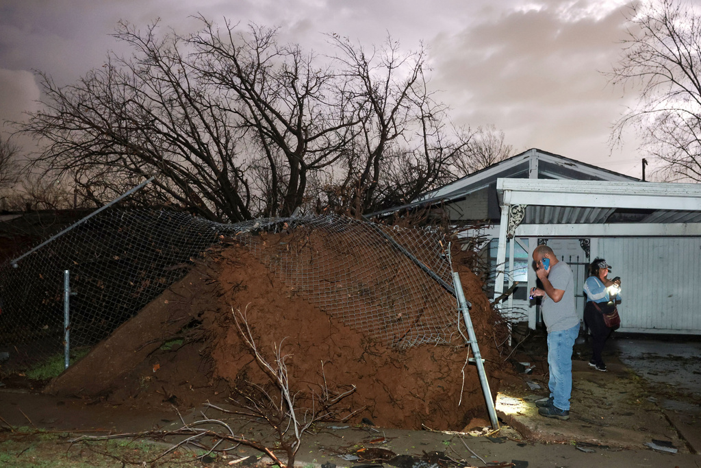 Carlos Lawrence and Miranda Turner view a downed tree from a storm on Friday, March 6, 2026 in Tulsa, Okla. (Mike Simons /Tulsa World via AP)