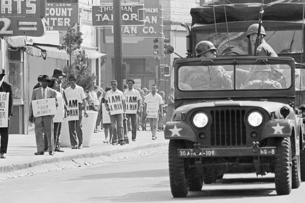FILE - Tennessee National Guard troopers in jeeps and trucks escort striking Memphis sanitation workers during a march through downtown Memphis, Tenn., March 30, 1968. (AP Photo, File)