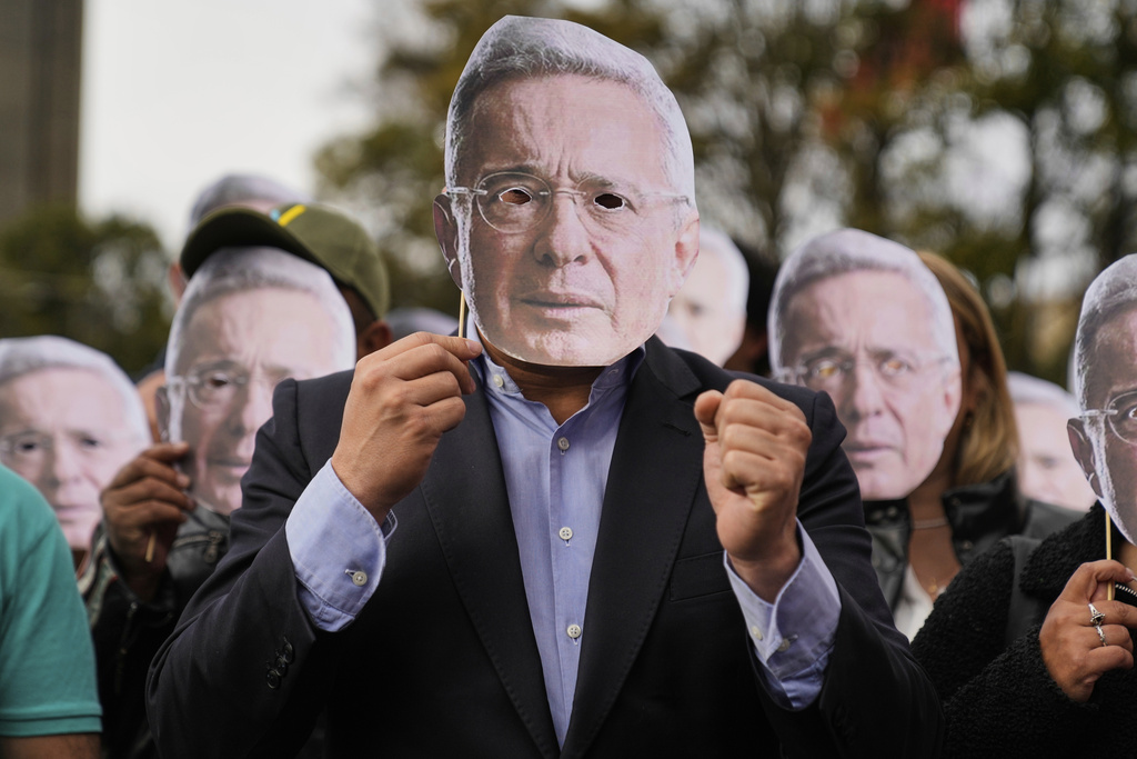 FILE - Supporters of former Colombian President Alvaro Uribe hold cutouts of his face outside the court where he was found guilty of witness tampering and bribery, in Bogota, Colombia, July 28, 2025. (AP Photo/Fernando Vergara, File)