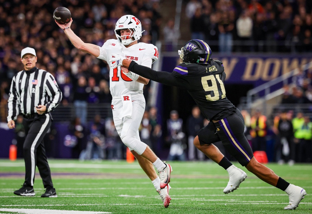 Washington defensive end Isaiah Ward, right, pressures Rutgers quarterback Athan Kaliakmanis, center, into throwing away the ball on third down during the first quarter of an NCAA college football game Friday, Oct. 10, 2025, in Seattle. (Nick Wagner/The Seattle Times via AP)