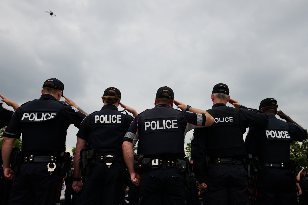Police salute during a procession with the body of Toronto Police Const. Marc Pinizzotto, who was killed in the line of duty, at the Chief Coroner's office in Toronto, Thursday, June 11, 2026. (Sammy Kogan/The Canadian Press via AP)