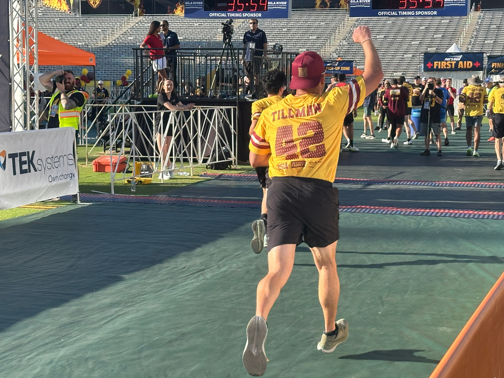 A runner celebrates as he reaches the finish line of Pat's Run, a 4.2-mile race honoring former NFL player and Army Ranger Pat Tillman, in Tempe, Ariz., on Saturday, April 11, 2026. (AP Photo/John Marshall)