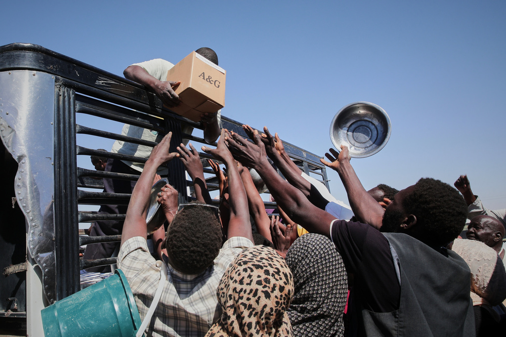 FILE.- Sudanese families displaced from El-Fasher reach out as aid workers distribute food supplies at the newly established El-Afadh camp in Al Dabbah, in Sudan's Northern State, Nov. 16, 2025. (AP Photo/Marwan Ali,File)