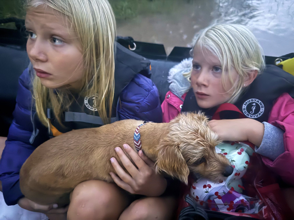 Ella and Grace Sanford and their dog Benjamin ride on a Texas Game Wardens rescue boat after being evacuated from their home after flooding in Uvalde, Texas, on Thursday, July 16, 2026. (Casy Sanford via AP)