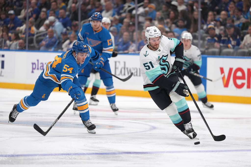 Seattle Kraken's Shane Wright (51) brings the puck down the ice as St. Louis Blues' Dalibor Dvorsky defends during the third period of an NHL hockey game Saturday, Nov. 8, 2025, in St. Louis. (AP Photo/Jeff Roberson)