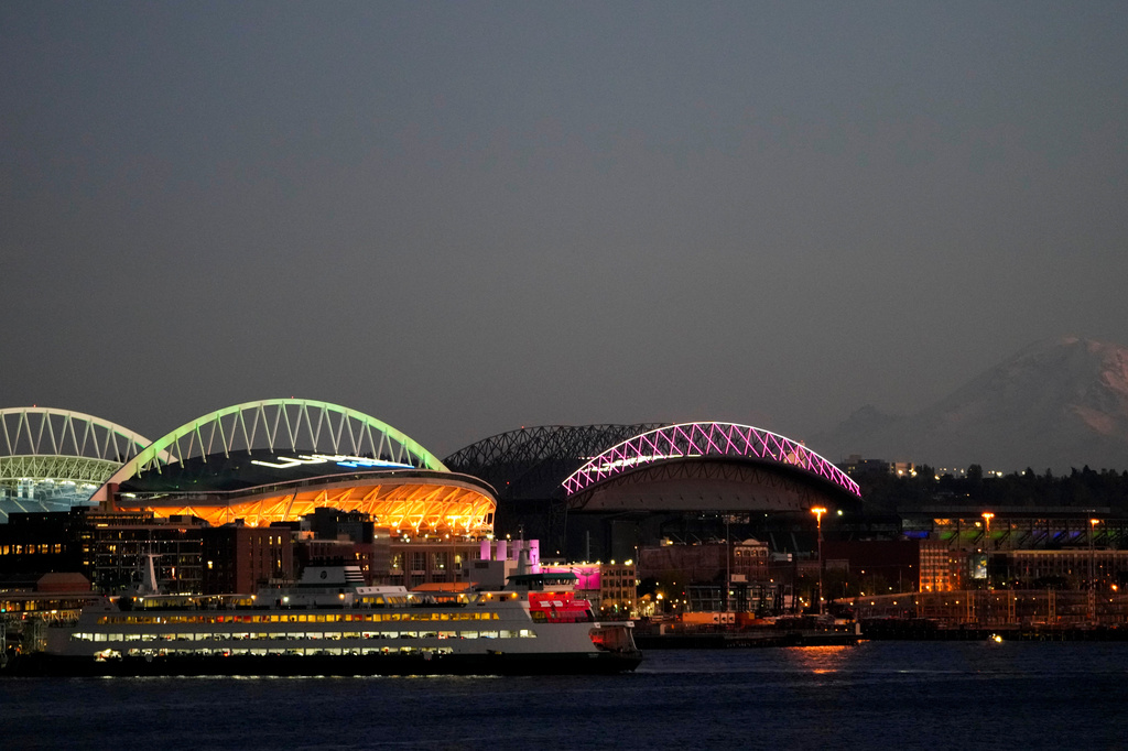 FILE - A Washington State ferry comes in to dock at the Seattle ferry terminal in front of Lumen Field, left, and T-Mobile Park, right, with Mount Rainier visible at right, as the sun sets Oct. 29, 2023, in Seattle. (AP Photo/Lindsey Wasson, File)