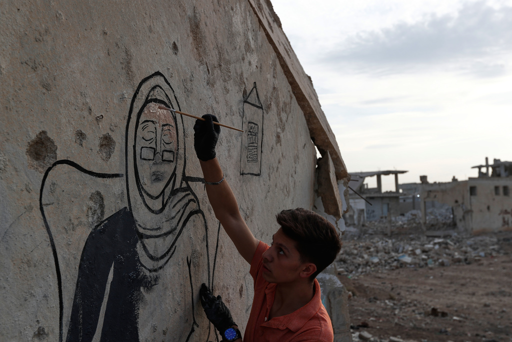 A group of Syrian graffiti artists paint a mural on the collapsed ceiling of a war-damaged house in Daraya, on the outskirts of Damascus, Syria, Monday, Nov. 3, 2025. (AP Photo/Omar Sanadiki)
