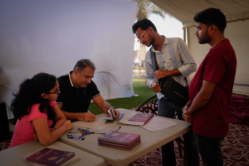 Stranded Indian travelers Mohammad Nahid, second right, and Amit Kumar, right, register their names at a farmhouse owned by an Indian businessman, now converted into a shelter in Ajman, near Dubai, United Arab Emirates, Saturday, March 7, 2026. (AP Photo/Altaf Qadri)