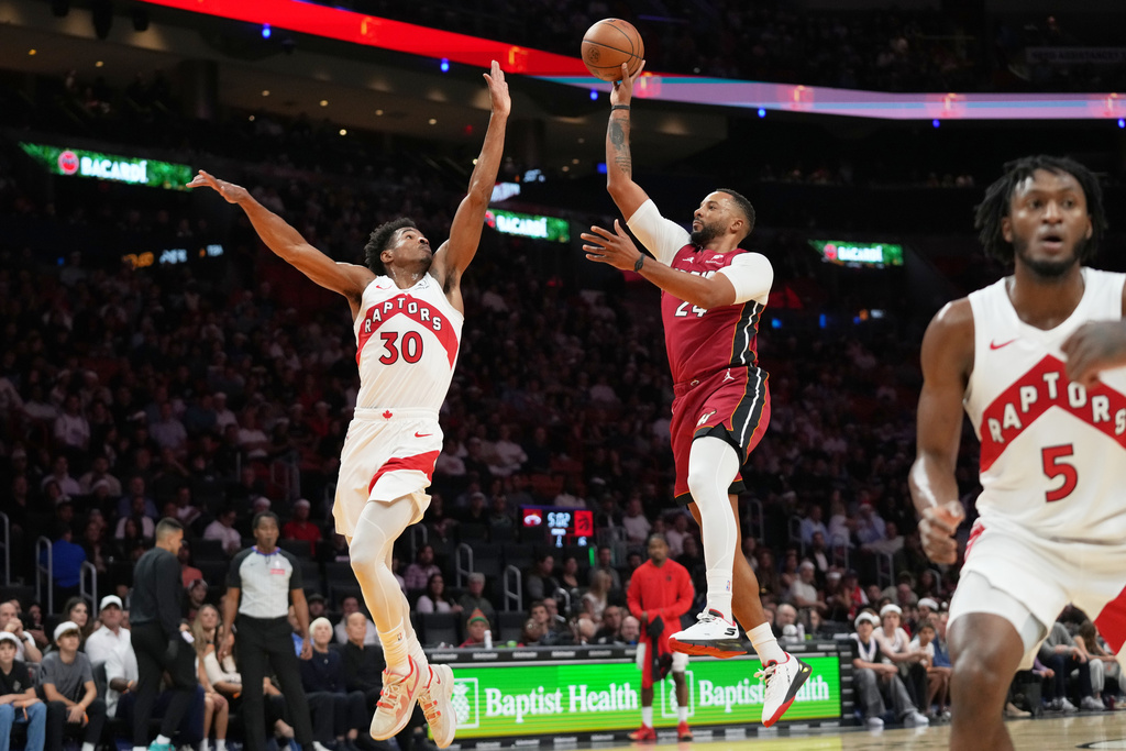 Miami Heat guard Norman Powell, right, goes to the basket as Toronto Raptors guard Ochai Agbaji (30) defends during the first half of an NBA basketball game, Tuesday, Dec. 23, 2025, in Miami. (AP Photo/Lynne Sladky)