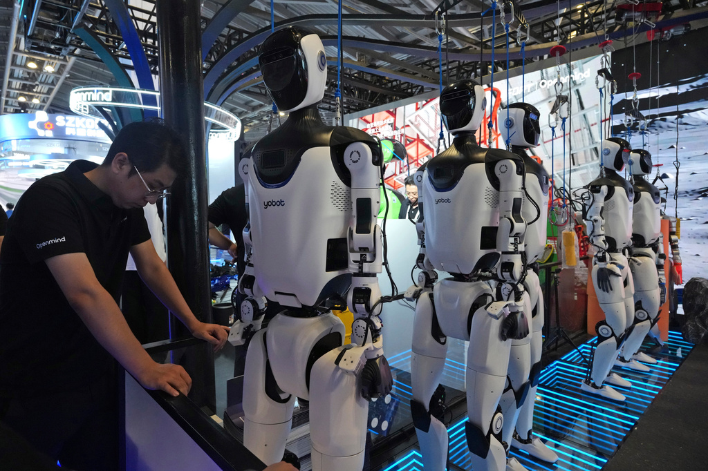 FILE - A worker reacts near a line of humanoid robots displayed at the World AI Conference in Shanghai, Friday, July 17, 2026. (AP Photo/Ng Han Guan, file)