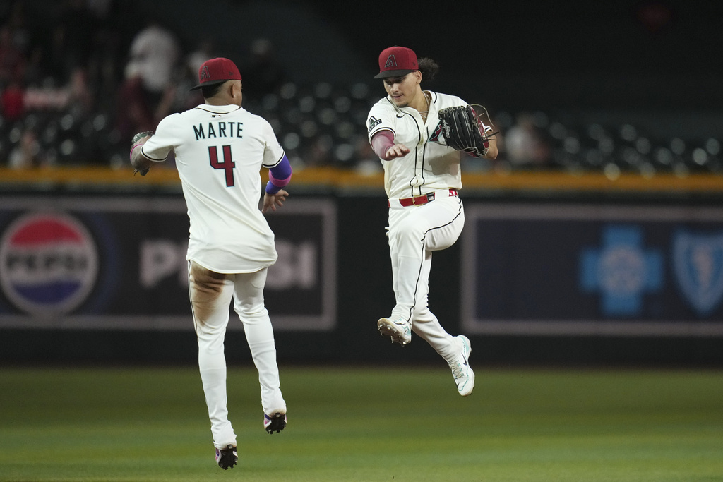 Arizona Diamondbacks' Ketel Marte (4) and Alek Thomas, right, celebrate a win against the Cleveland Guardians after a baseball game Tuesday, Aug. 19, 2025, in Phoenix. (AP Photo/Ross D. Franklin)