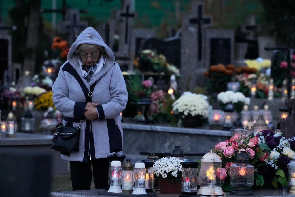 A women observe All Saints' Day, a time for reflecting on those who have died, in Kroczewo near Warsaw, Poland, Saturday, Nov. 1, 2025. (AP Photo/Czarek Sokolowski)