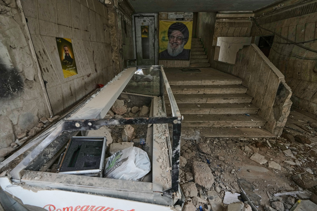 A portrait of the late Hezbollah leader Sayyed Hassan Nasrallah, center, hangs at the entrance of a building damaged in an Israeli airstrike in Dahiyeh, Beirut's southern suburbs, Lebanon, Saturday, April 4, 2026. (AP Photo/Bilal Hussein)