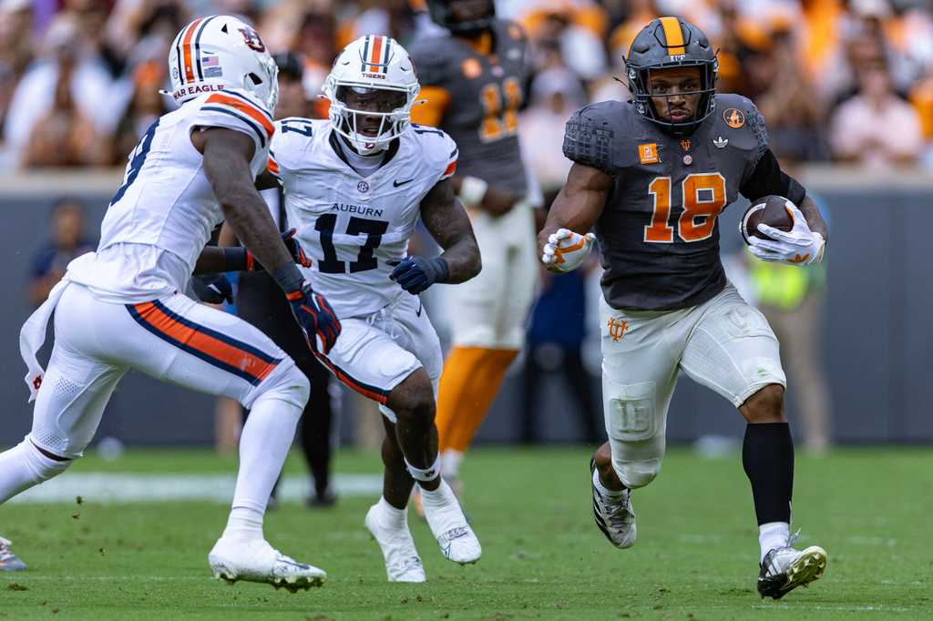 Tennessee running back DeSean Bishop (18) runs for yardage as he is chased by Auburn linebackers Xavier Atkins (17) and Elijah Melendez, left, during the first half of an NCAA college football game Saturday, Oct. 3, 2026, in Knoxville, Tenn. (AP Photo/Wade Payne)