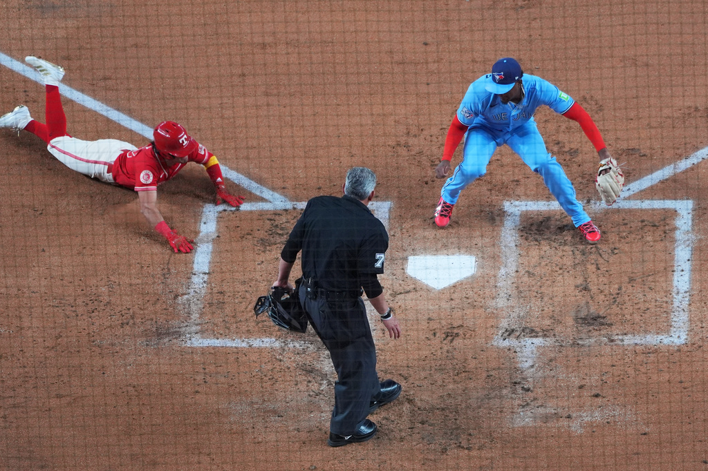 Texas Rangers' Nicky Lopez, left, prepares to slide into home ahead of the tag by Toronto Blue Jays starting pitcher JosÈ Soriano, right, as home plate umpire Manny Gonzalez looks on during the second inning of a baseball game Saturday, Sept. 19, 2026, in Arlington, Texas. (AP Photo/Julio Cortez)