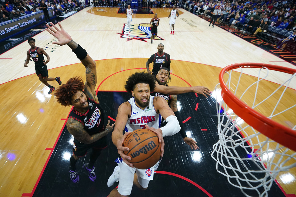 Detroit Pistons' Cade Cunningham, center, goes up for a shot against Philadelphia 76ers' Kelly Oubre Jr., left, and Trendon Watford during the second half of an NBA basketball game Sunday, Nov. 9, 2025, in Philadelphia. (AP Photo/Matt Slocum)