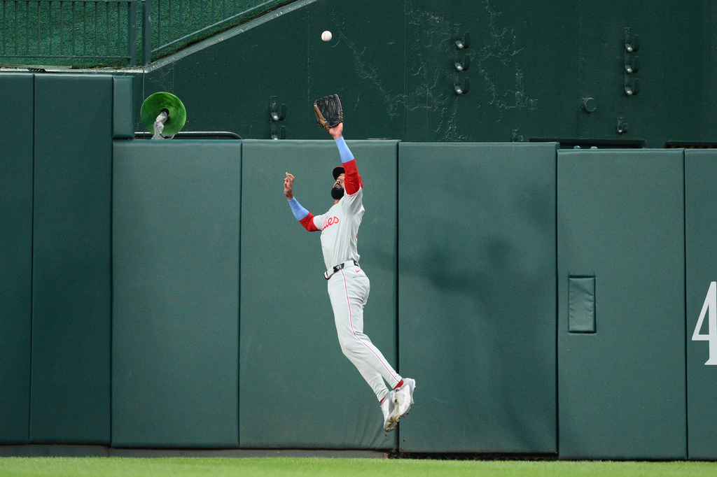 Philadelphia Phillies center fielder Derek Hill leaps up to make a catch on a fly ball by Washington Nationals' Dylan Crews for an out during the first inning of a baseball game, Tuesday, Sept. 15, 2026, in Washington. (AP Photo/Nick Wass)