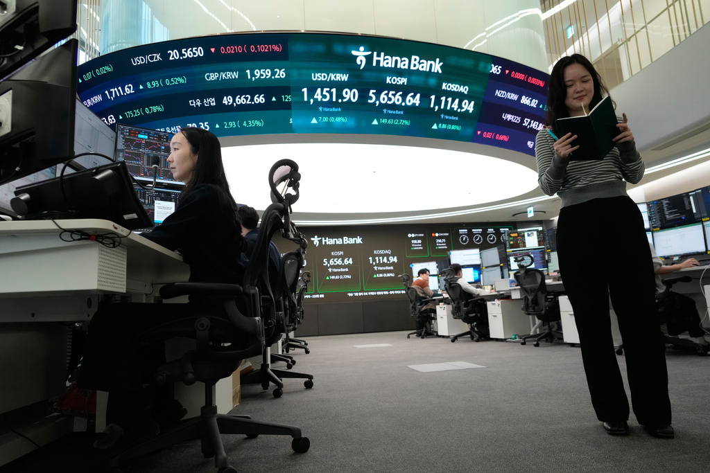 Currency traders work near a screen showing the Korea Composite Stock Price Index (KOSPI), top center, and the foreign exchange rate between U.S. dollar and South Korean won, top center left, at the foreign exchange dealing room of the Hana Bank headquarters in Seoul, South Korea, Thursday, Feb. 19, 2026. (AP Photo/Ahn Young-joon)
