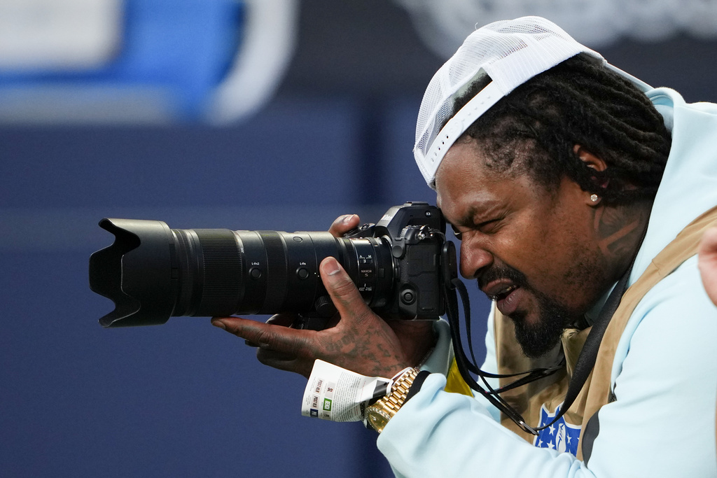 Former NFL player Marshawn Lynch takes photos during an NFL preseason football game between the Seattle Seahawks and the Las Vegas Raiders, Thursday, Aug. 7, 2025, in Seattle. (AP Photo/Lindsey Wasson)