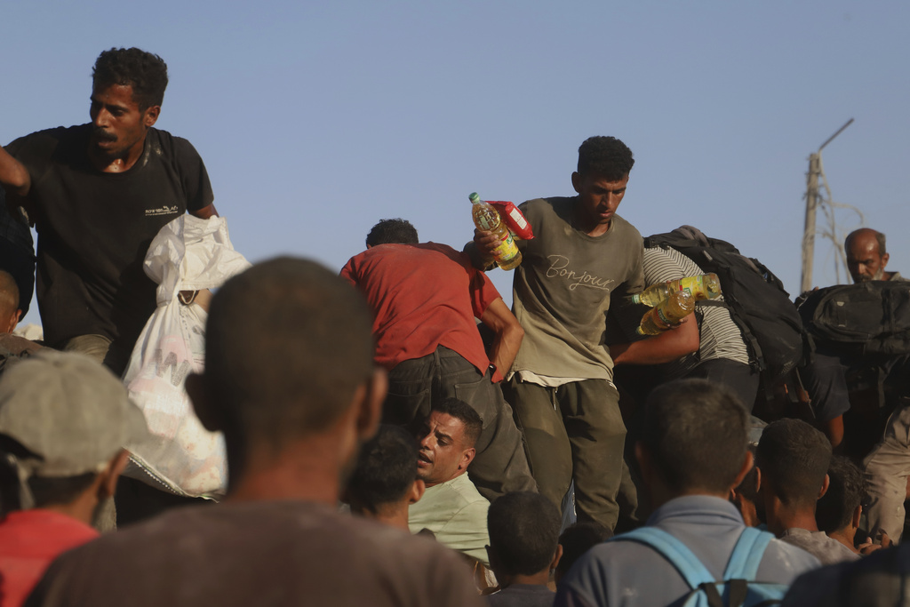 FILE - Palestinians struggle to get food and humanitarian aid from the back of a truck as it moves along the Morag corridor near Rafah, in the southern Gaza Strip, Monday, Aug. 4, 2025. (AP Photo/Mariam Dagga, File)