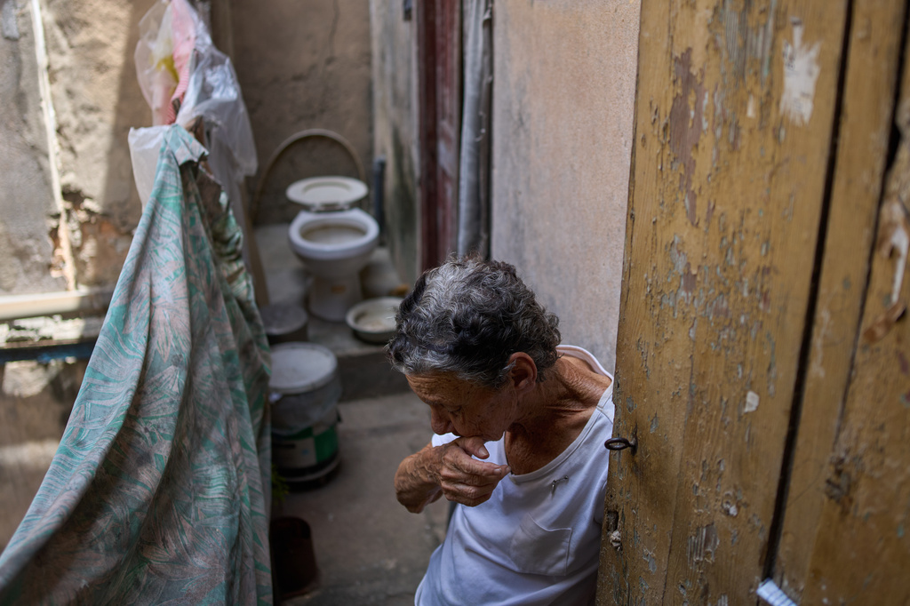Mercedes Lopez Rey, 83, stands in her bathroom, holding open a patio door as a visitor leaves her one-room apartment in Old Havana, Friday, April 10, 2026. (AP Photo/Ramon Espinosa)
