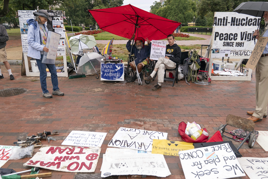 Philipos Melaku-Bello, center left, and Will Rosin, center right, flash the V sign during Peace Vigil in Lafayette Park across from the White House in Washington, Sunday, Sept. 7, 2025. The U.S. (AP Photo/Jose Luis Magana)
