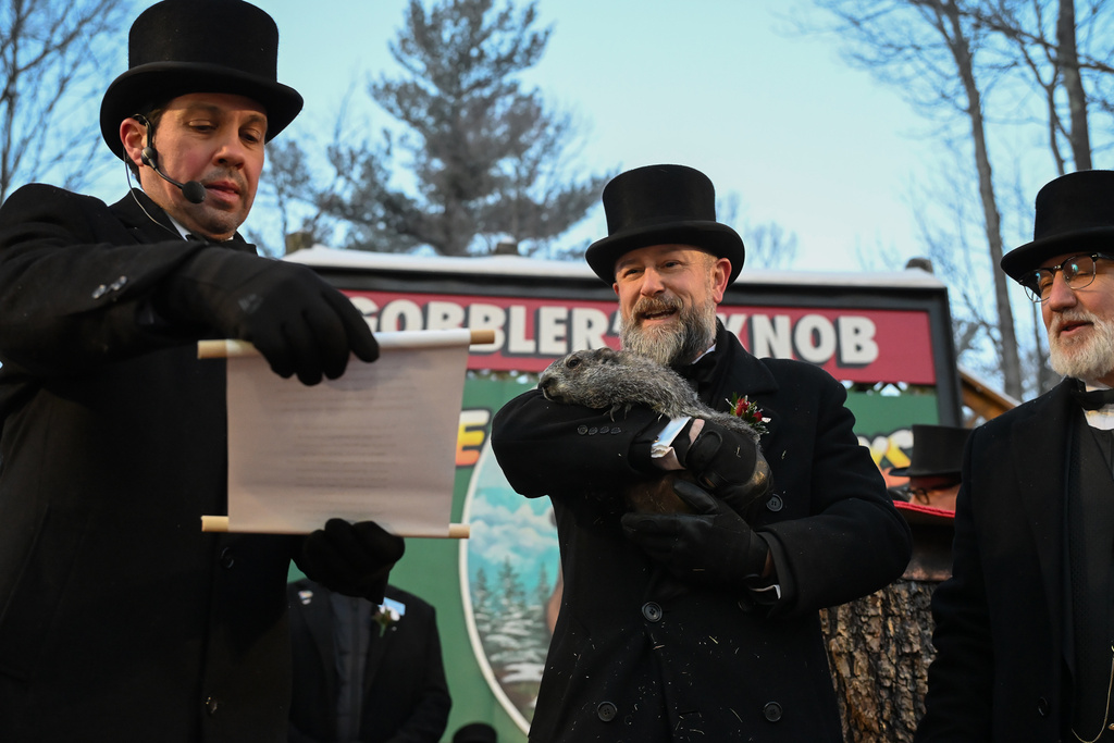 Groundhog Club Vice President Dan McGinley reads the scroll as handler A.J. Dereume holds Punxsutawney Phil, the weather prognosticating groundhog, during the 140th celebration of Groundhog Day on Gobbler's Knob in Punxsutawney, Pa., Monday, Feb. 2, 2026, Phil's handlers said that the groundhog has forecast six more weeks of winter. (AP Photo/Barry Reeger)