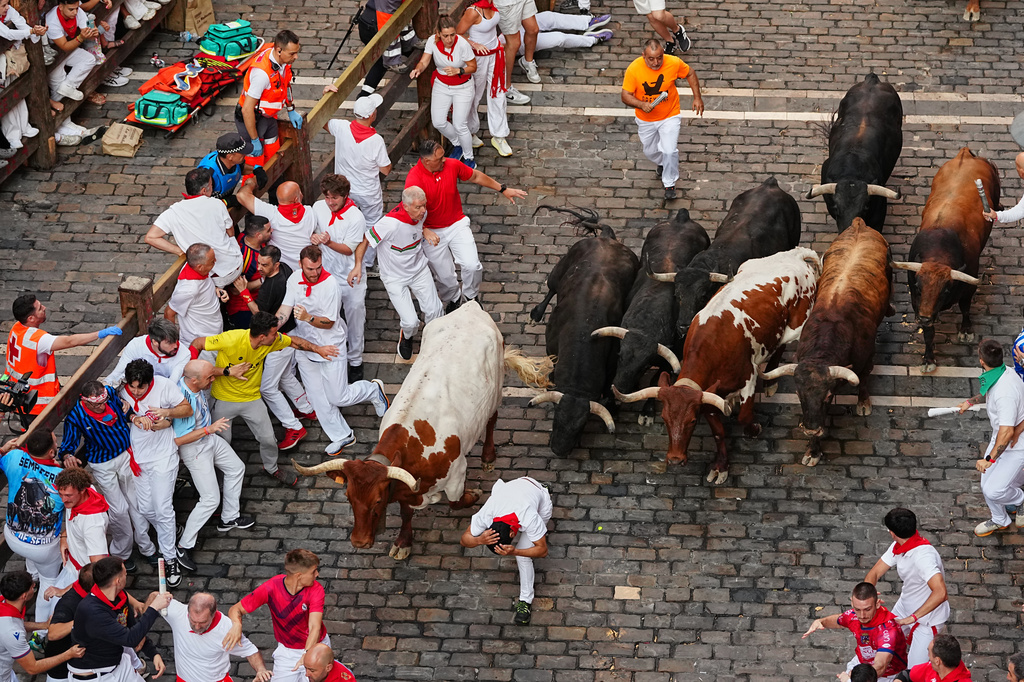 Revelers run alongside Victoriano del Río's fighting bulls during the third running of the bulls at the San Fermín festival in Pamplona, Spain, Thursday, July 9, 2026. (AP Photo/Miguel Oses)
