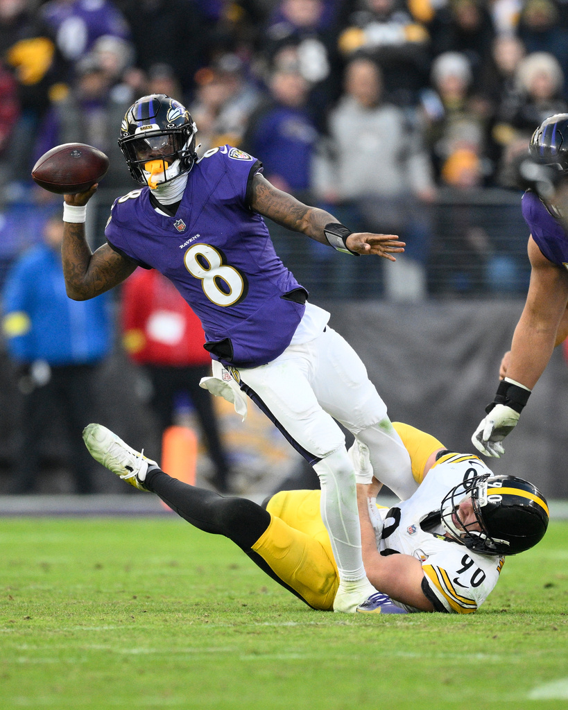 Baltimore Ravens quarterback Lamar Jackson (8) throws while being tackled by Pittsburgh Steelers linebacker T.J. Watt (90) during the second half of an NFL football game, Sunday, Dec. 7, 2025, in Baltimore. (AP Photo/Nick Wass)