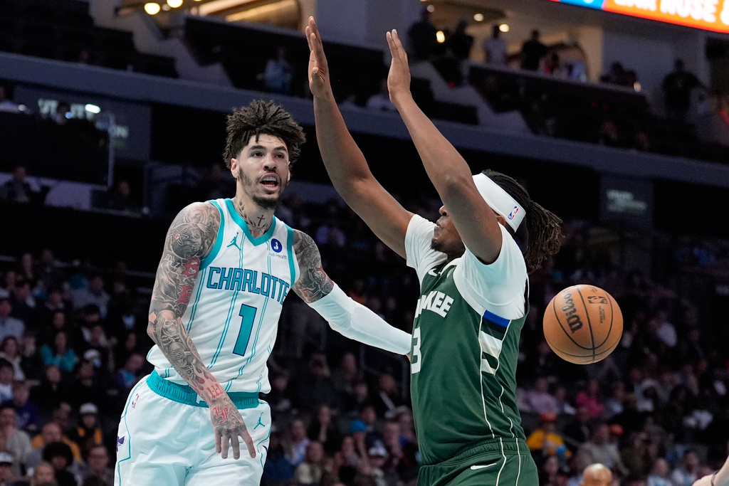 Charlotte Hornets guard Lamelo Ball passes around Milwaukee Bucks center Myles Turner during the first half of an NBA basketball game, Monday, Dec. 29, 2025, in Charlotte, N.C. (AP Photo/Chris Carlson)