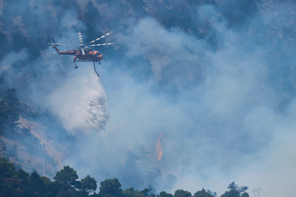 A firefighting helicopter drops water over a wildfire on Mount Kithairon near Porto Germeno, northwest of Athens, Greece, Monday, Aug. 3, 2026. (AP Photo/Petros Giannakouris)