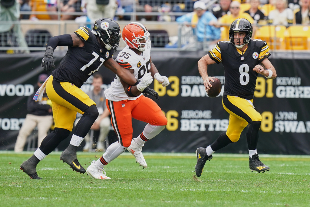 Pittsburgh Steelers quarterback Aaron Rodgers (8) scrambles as he is pursued by Cleveland Browns defensive end Myles Garrett (95) in the first half of an NFL football game in Pittsburgh, Sunday, Oct. 12, 2025. (AP Photo/Matt Freed)