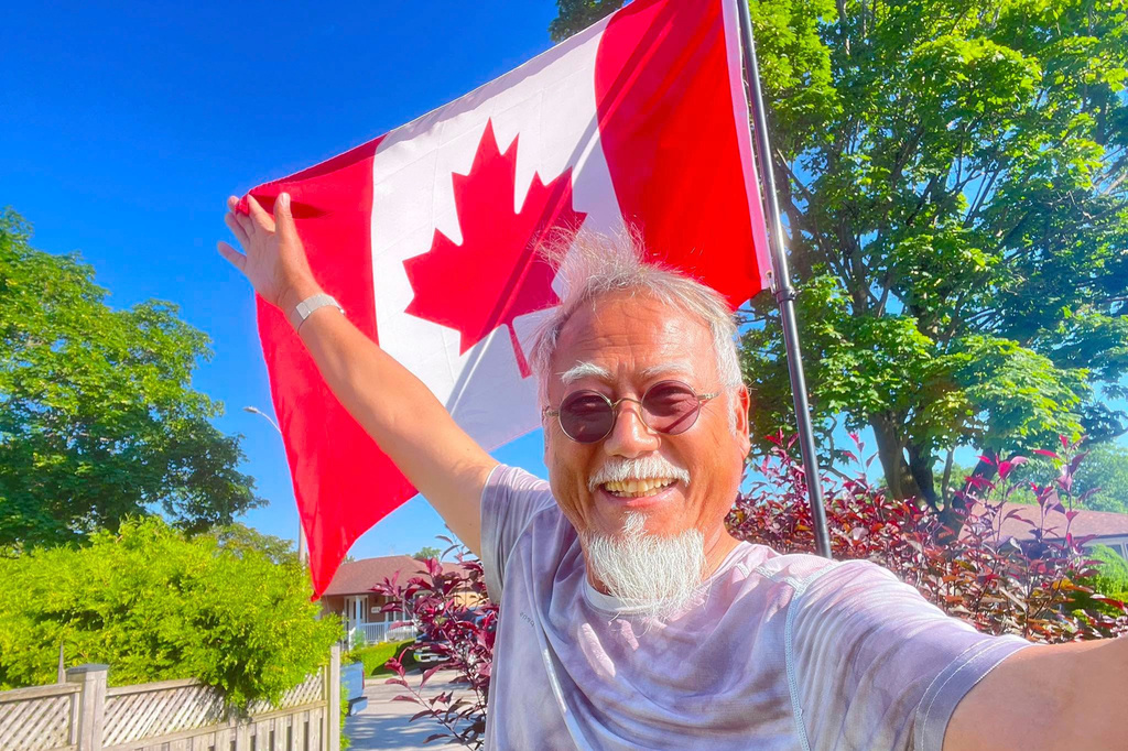 In this photo released by Dong Guangping, Dong Guangping poses for a photo with the Canadian flag after arriving in Toronto, Canada, on June 27, 2026. (Dong Guangping via AP)