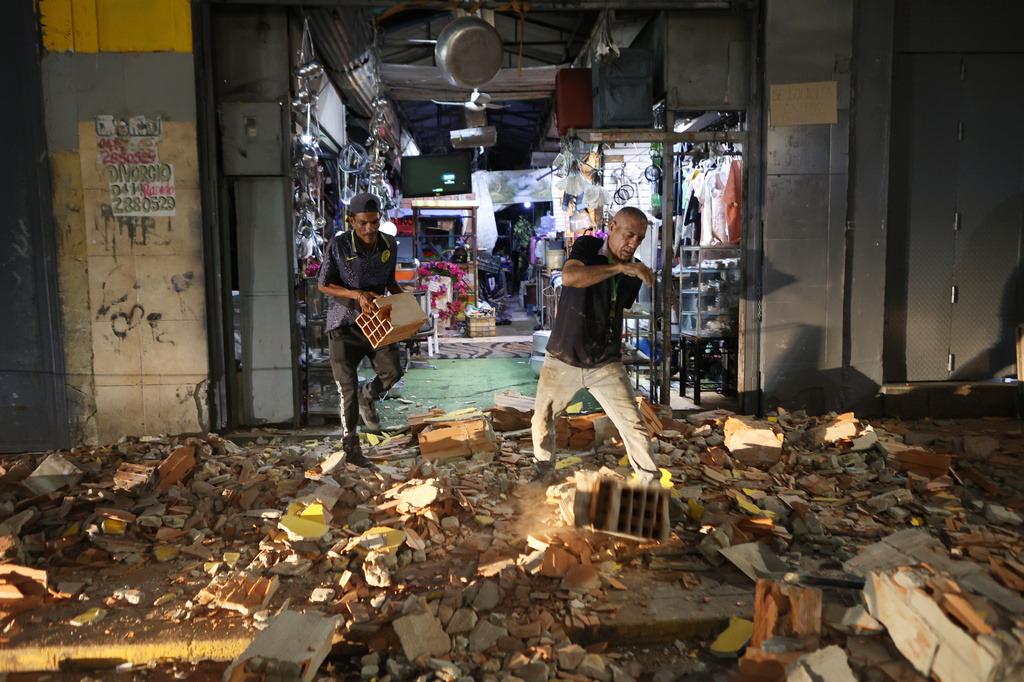 Men walk among rubble after an earthquake in Caracas, Venezuela, Wednesday, June 24, 2026. (AP Photo/Pedro Mattey)