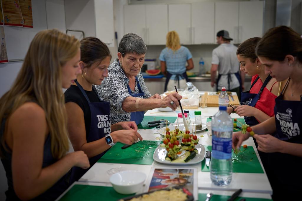 Nuria Isanda, 75, third from left, teaches tourists how to prepare and present traditional Spanish dishes during a cooking workshop at Grandmas Cooking in Barcelona, Spain, Wednesday, Oct. 14, 2026. (AP Photo/Emilio Morenatti)