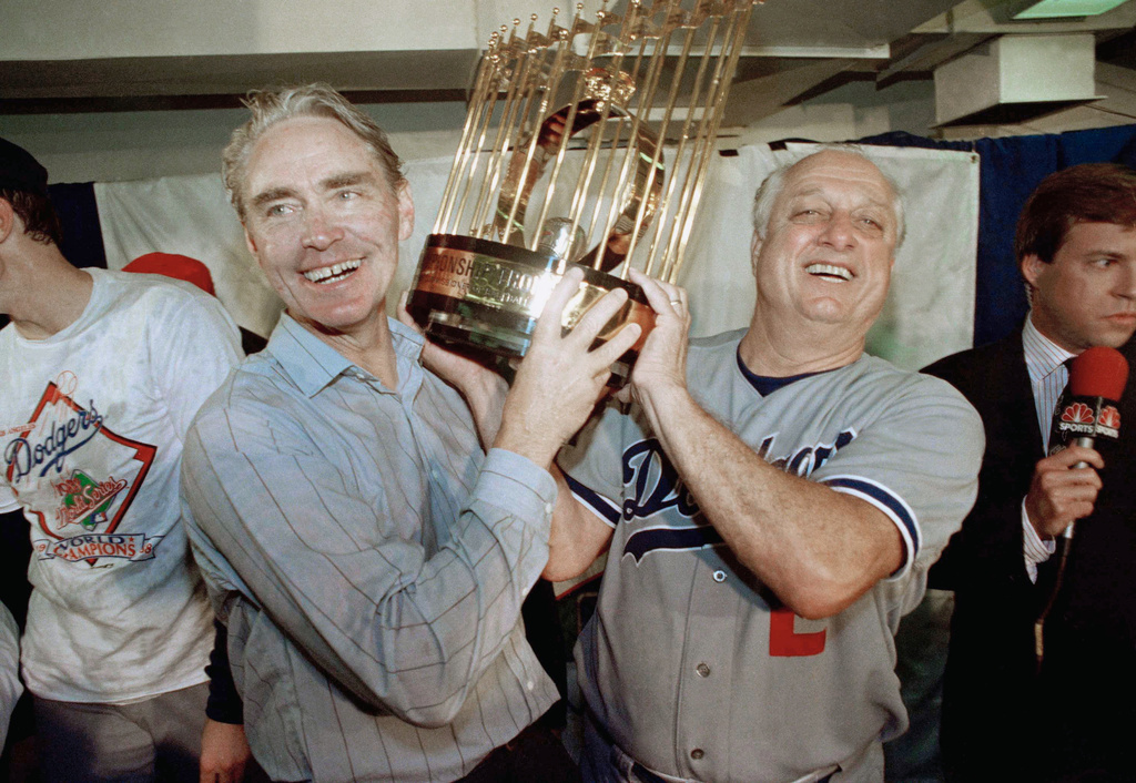 FILE - Los Angeles Dodgers manager Tommy Lasorda, right, and Fred Claire, Dodgers' vice president, hoist the World Series Trophy following their team's decisive 5-2 win over the Oakland A's in Oakland, Oct. 20, 1987. (AP Photo/Bill Beattie, File)