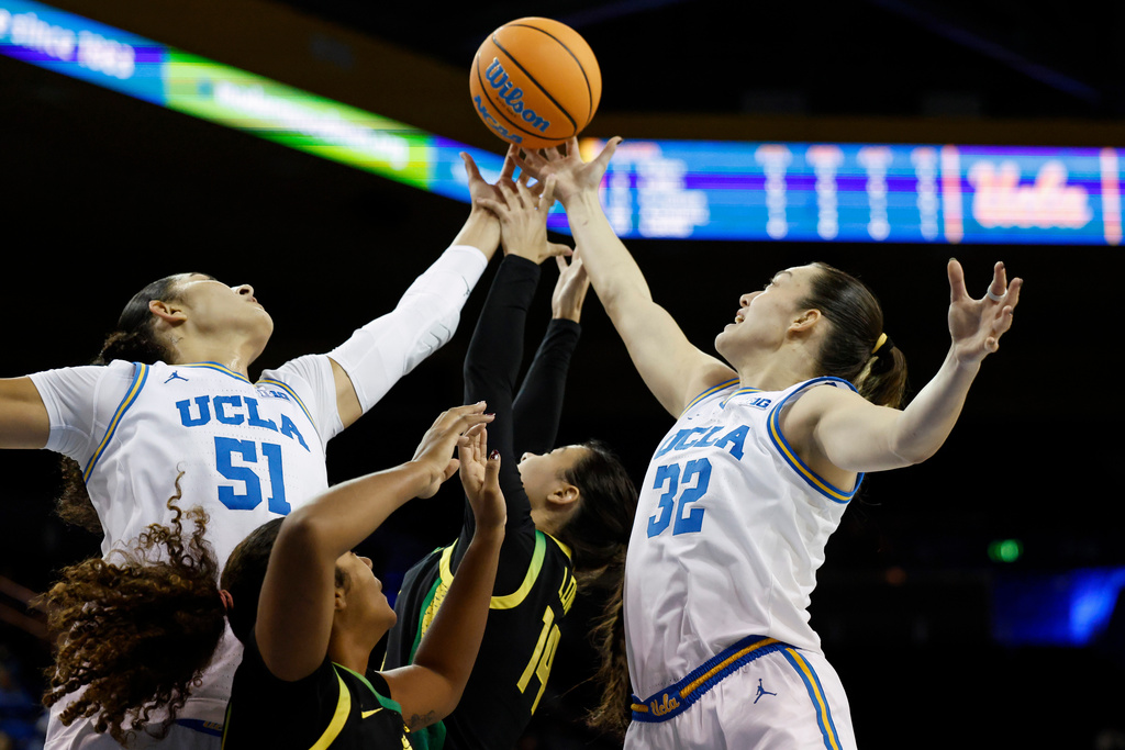 UCLA center Lauren Betts (51), Oregon forward Ehis Etute, second from left, Oregon guard Ari Long (14) and Oregon forward Angela Dugalić (32) reach for the ball during the first half of an NCAA college basketball game Sunday, Dec. 7, 2025, in Los Angeles. (AP Photo/Caroline Brehman)