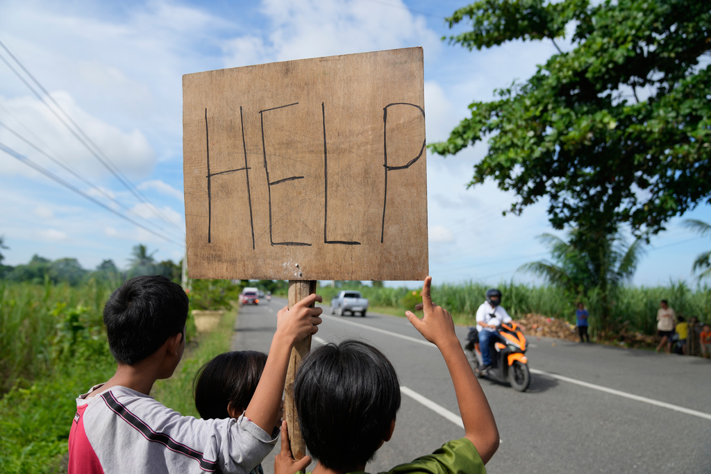 Earthquake survivors hold a "Help" sign along a road Thursday, Oct. 2, 2025, days after a strong quake struck in Medellin, Cebu Province, Central Philippines. (AP Photo/Aaron Favila)