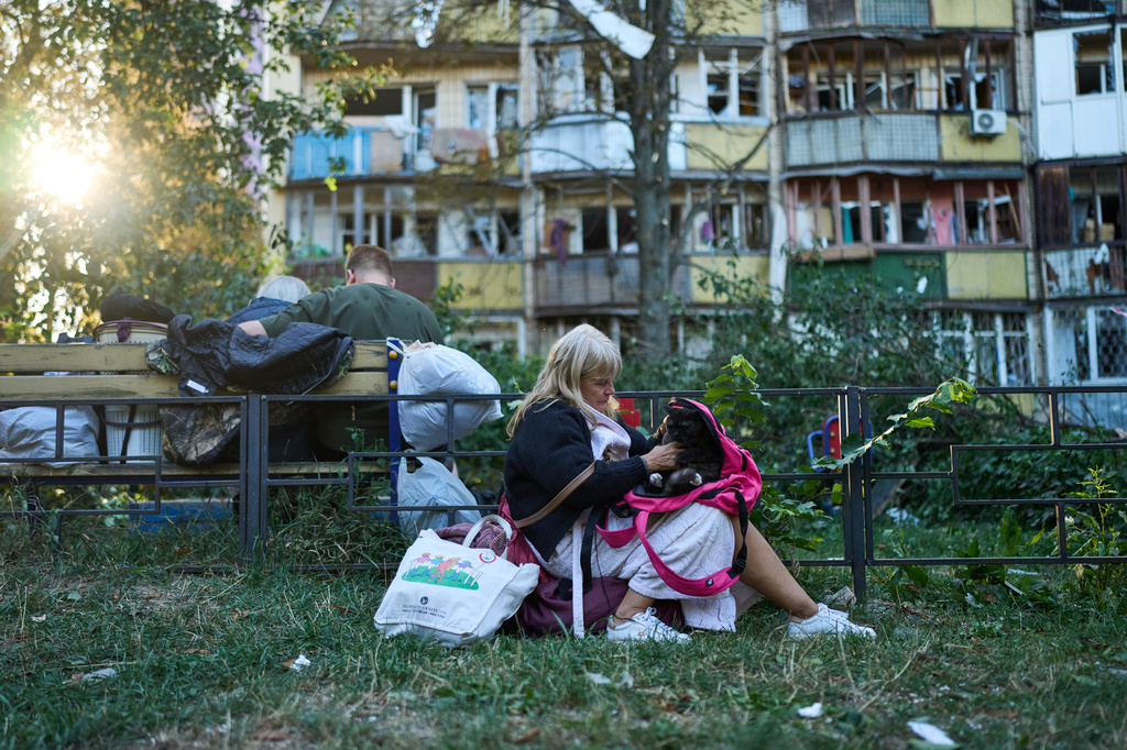 Local residents sit in front of heavily damaged residential buildings after an overnight Russian attack, in Kyiv, Ukraine, Thursday, Aug. 20, 2026. (AP Photo/Francisco Seco)