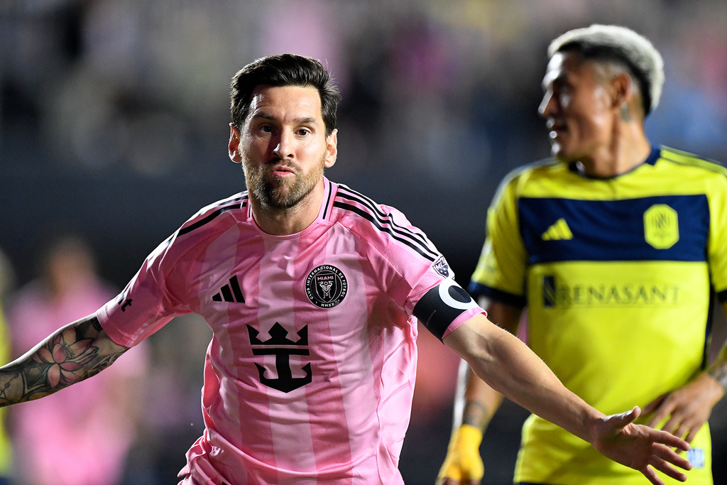 Inter Miami forward Lionel Messi, left, celebrates after scoring in front of Nashville SC midfielder Andy Najar, right, during the first half of Game 3 in the first round of MLS soccer's Western Conference playoffs in Fort Lauderdale, Fla., Nov. 8, 2025. (AP Photo/Michael Laughlin)