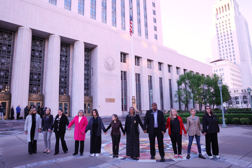 FILE - A group holds hands outside a landmark trial over whether social media platforms deliberately addict and harm children, Wednesday, Feb. 18, 2026, in Los Angeles. (AP Photo/Ryan Sun, File)