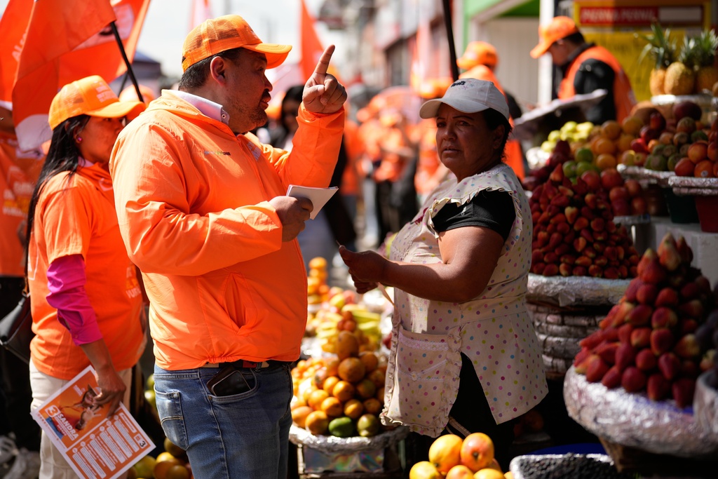 Congressman Carlos Carreño Marín, who goes by Sergio Marin, of the Comunes party, talks with a vendor while campaigning for reelection ahead of legislative elections in Bogota, Colombia, Thursday, Feb. 26, 2026. (AP Photo/Fernando Vergara)