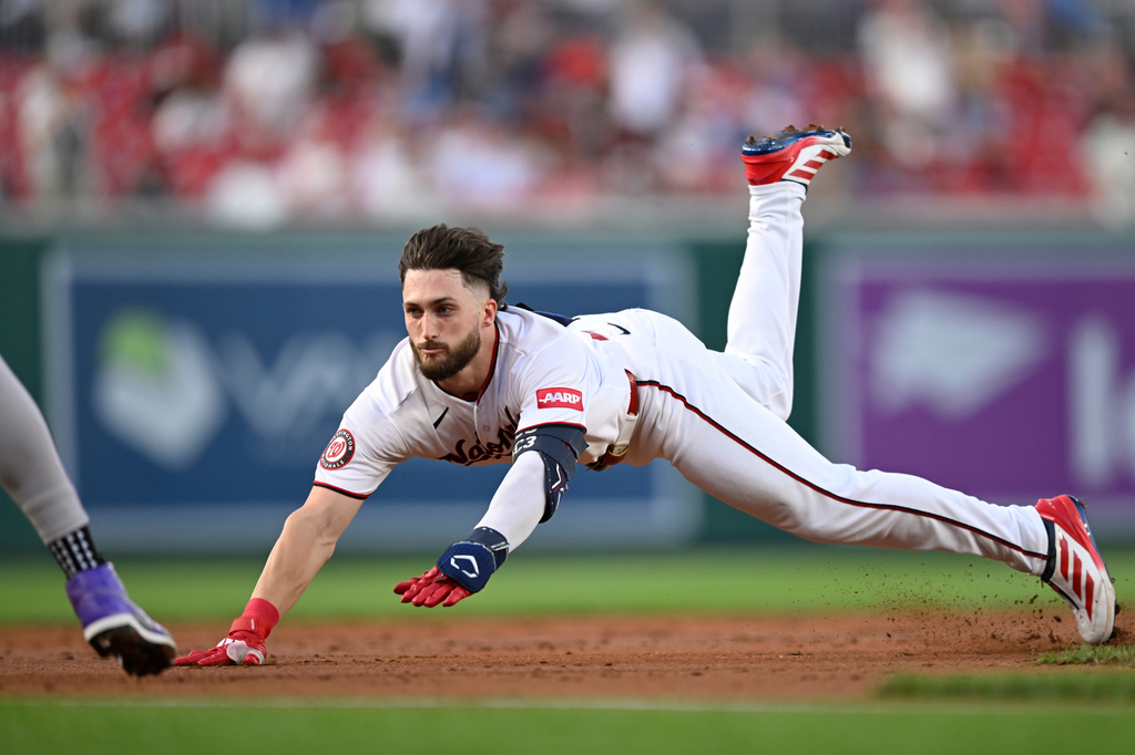 Washington Nationals' Dylan Crews dives into third base for a triple during the first inning of a baseball game against the Colorado Rockies, Wednesday, Aug. 26, 2026, in Washington. (AP Photo/John McDonnell)