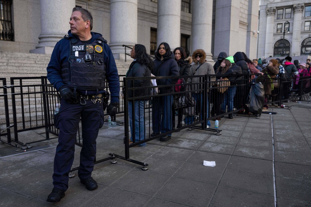 US Marshall Service officer stand while people wait in line outside Manhattan federal court ahead of a hearing for Luigi Mangione, Friday, Jan. 9, 2026, in New York. (AP Photo/Yuki Iwamura)