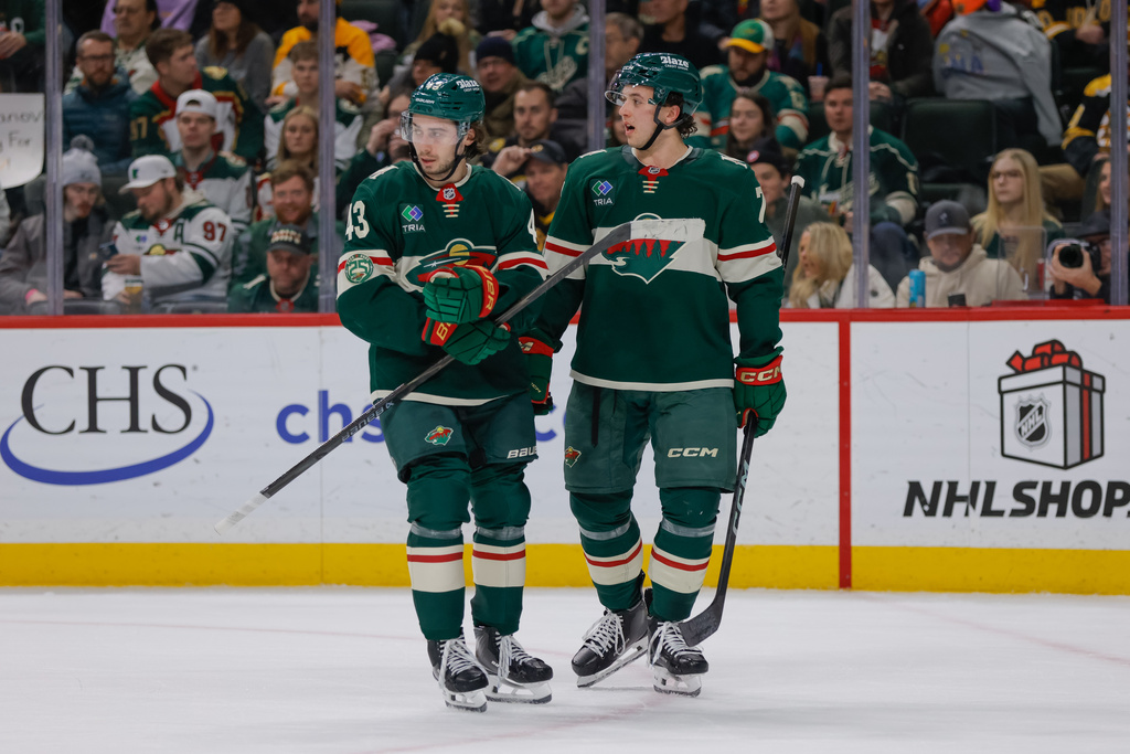 Minnesota Wild defenseman Brock Faber (7) talks with defenseman Quinn Hughes (43) during the first period of an NHL hockey game against the Boston Bruins, Sunday, Dec. 14, 2025, in St. Paul, Minn. (AP Photo/Bailey Hillesheim)