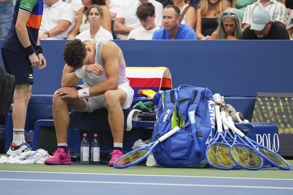Ben Shelton, of the United States, reacts on the bench before retiring against Adrian Mannarino, of France, during the third round of the U.S. Open tennis championships, Friday, Aug. 29, 2025, in New York. (AP Photo/Kirsty Wigglesworth)