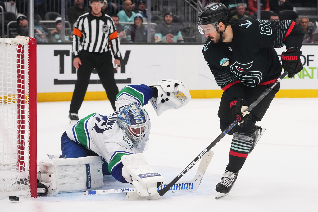 Seattle Kraken center Frederick Gaudreau has his shot blocked by Vancouver Canucks goaltender Kevin Lankinen, left, during a shootout in an NHL hockey game Monday, Dec. 29, 2025, in Seattle. (AP Photo/Lindsey Wasson)