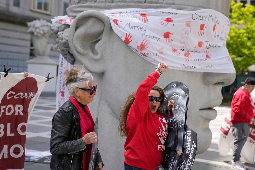 Stacy Schwab, center, and others react after hearing that a hearing for for Purdue Pharma had been rescheduled while relying outside a courthouse in Newark, N.J., Tuesday, April 21, 2026. (AP Photo/Seth Wenig)