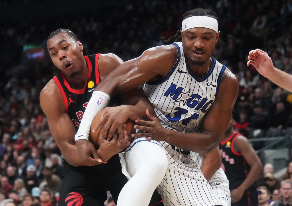 Toronto Raptors' Scottie Barnes (left) and Orlando Magic's Wendell Carter Jr. (34) battle for the ball during the first half of an NBA Cup basketball game in Toronto, Friday, Oct. 30, 2026. (Nathan Denette/The Canadian Press via AP)
