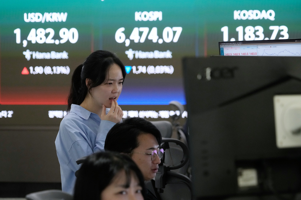 A currency trader watches monitors near a screen showing the Korea Composite Stock Price Index (KOSPI), top center, and the foreign exchange rate between U.S. dollar and South Korean won, top center left, at the foreign exchange dealing room of the Hana Bank headquarters in Seoul, South Korea, Friday, April 24, 2026. (AP Photo/Ahn Young-joon)